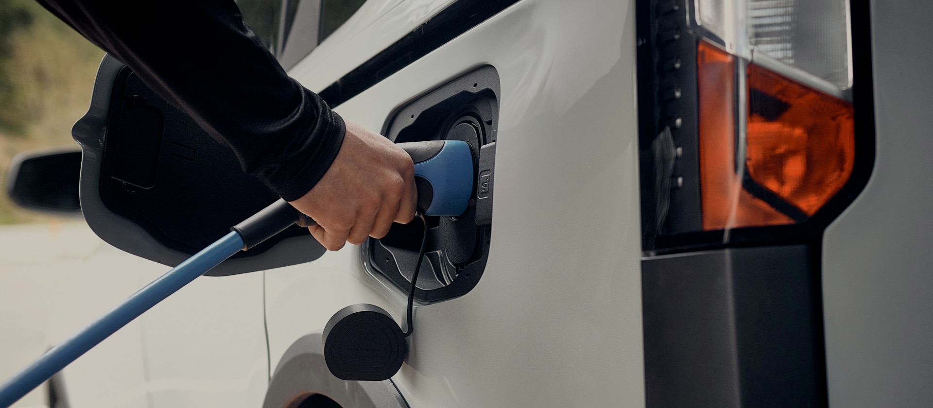 Közelkép egy fehér Ford elektromos járműről, melyet elektromos töltőre csatlakoztatnak.