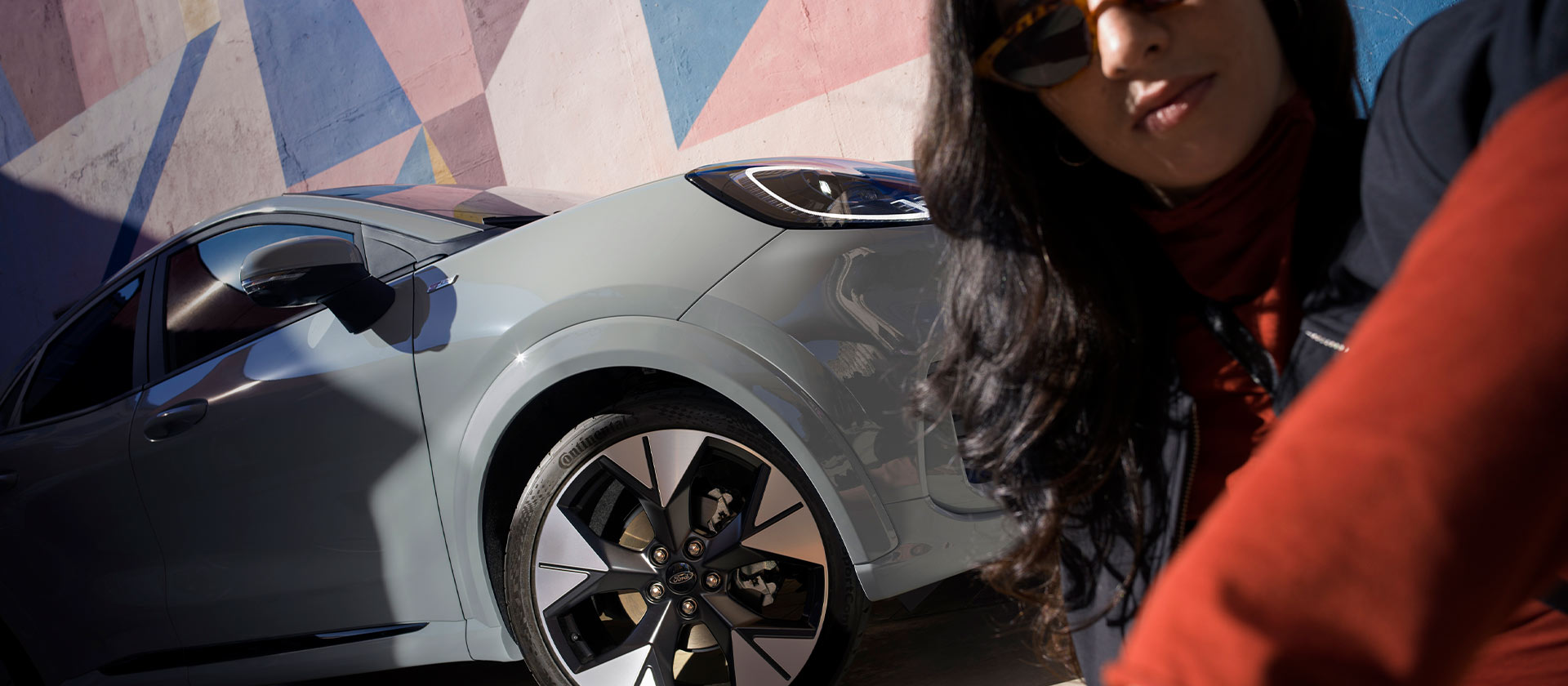 Ezüstszínű Ford Puma mild hibrid autó mellett ülő személy.