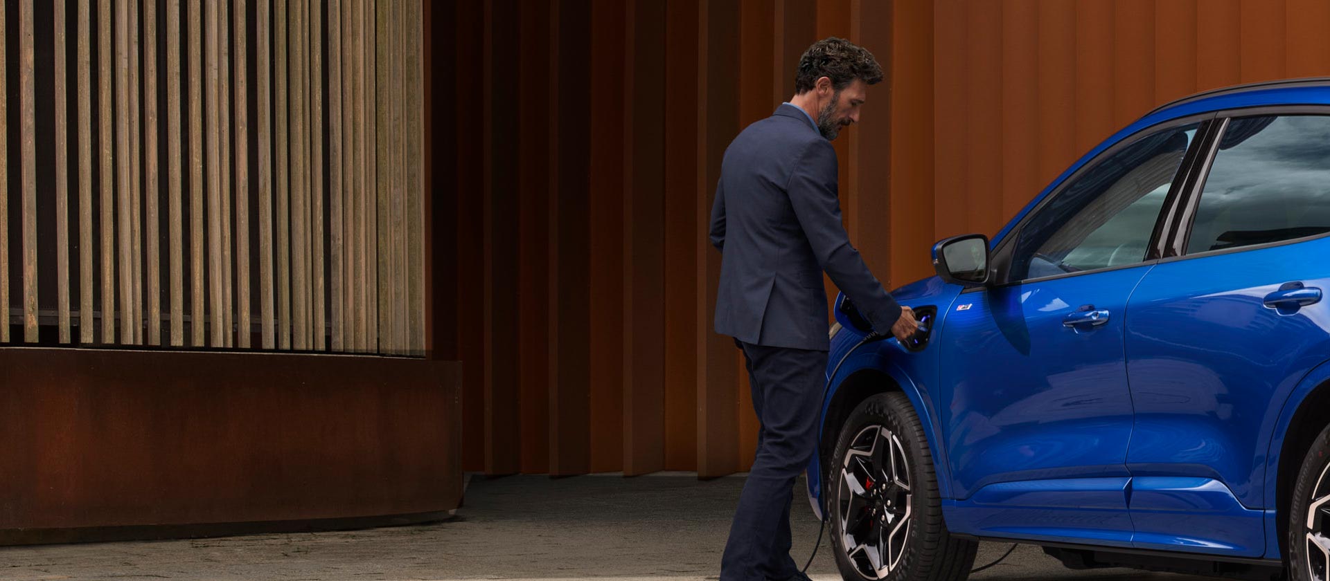 Ford plug-in hibrid autót otthoni EV töltőkábelhez csatlakoztató személy.