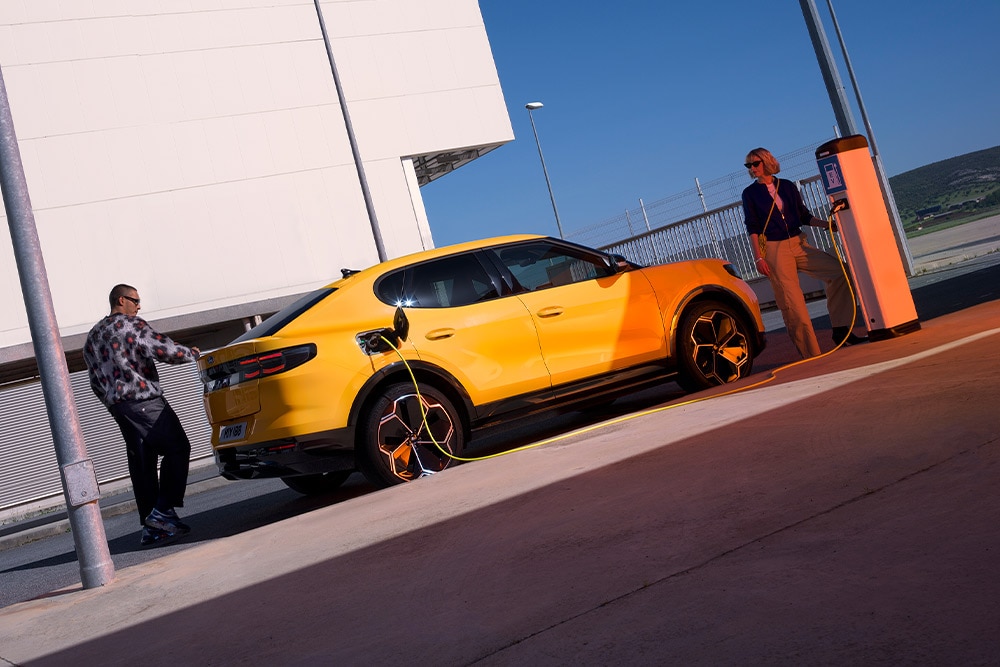 Sárga Ford Capri EV-t köztéri töltőállomáson töltő személy.