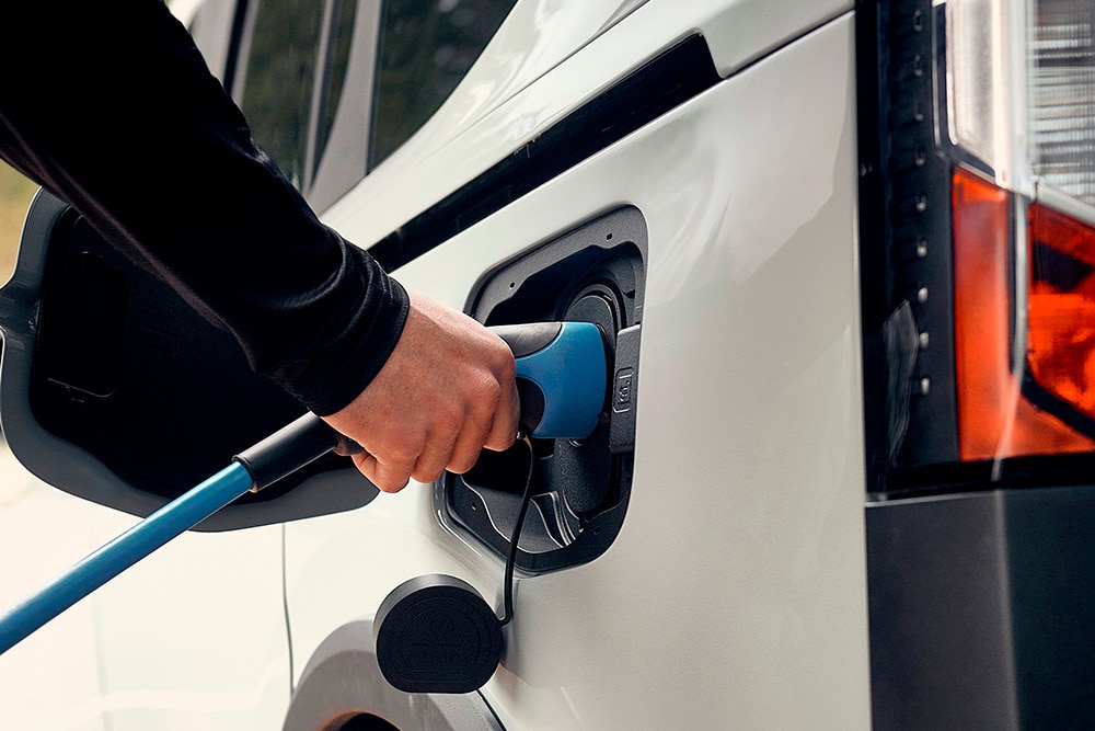 Ford elektromos járművet EV töltőkábelhez csatlakoztató személy.