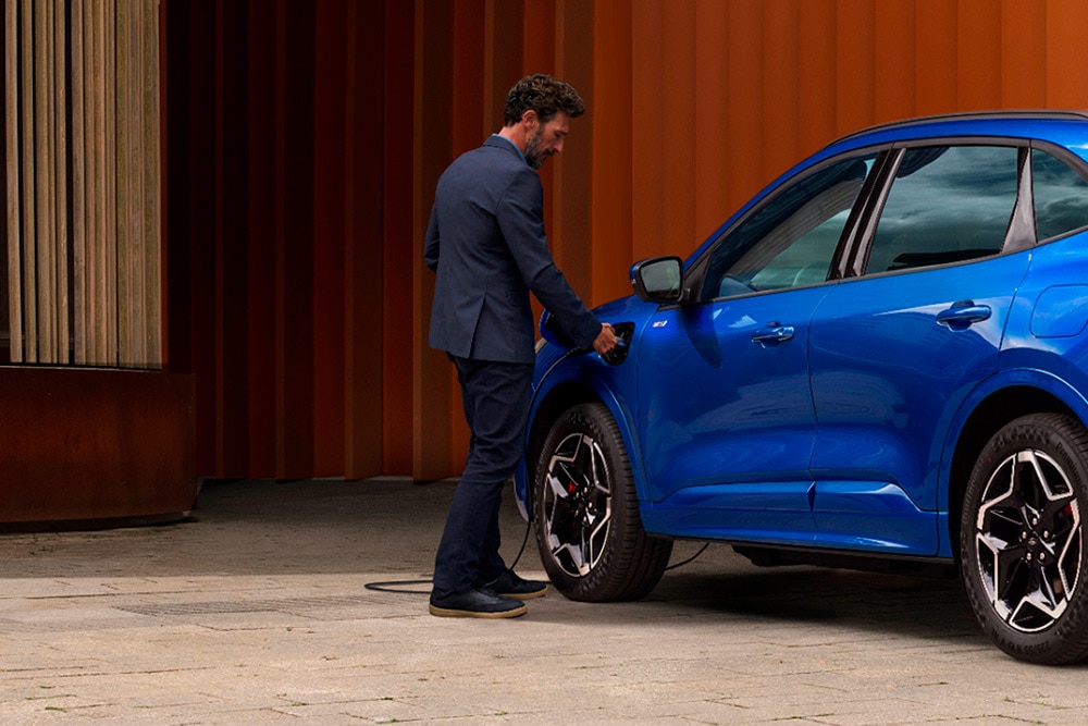 Ford plug-in hibrid autóhoz EV otthoni töltőkábelt csatlakoztató személy.