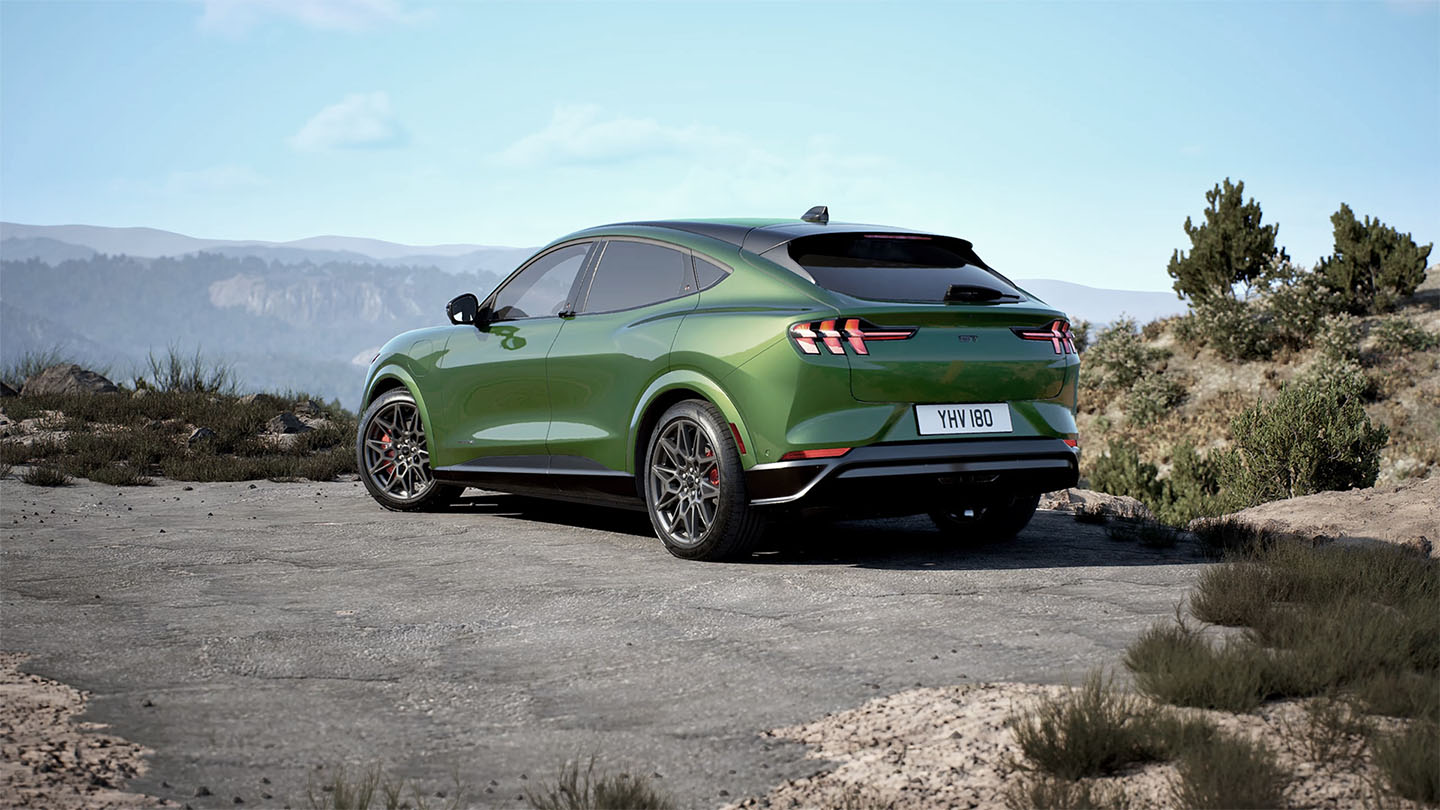 Eruption Green színű, hegyi úton parkoló  Mustang Mach-E GT hátulja.