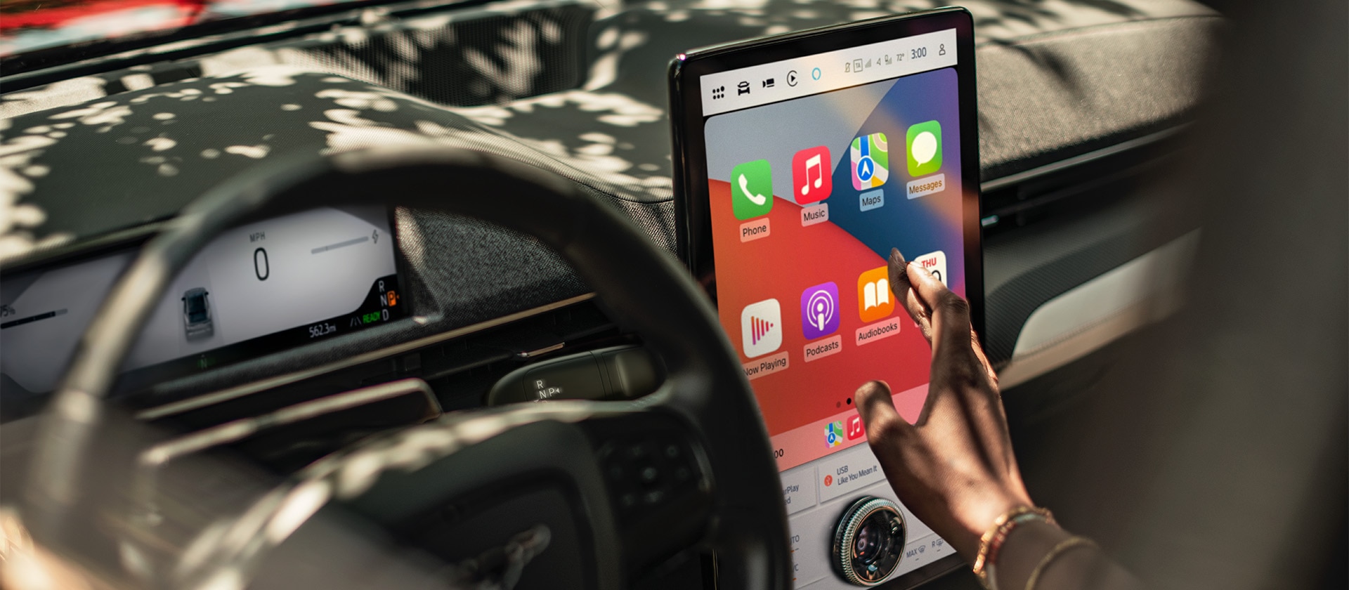 Közelképen egy Ford Mustang Mach-E-t vezető személy, aki a 15,5''-os SYNC 4 érintőképernyőn az Apple CarPlay-t használja. 