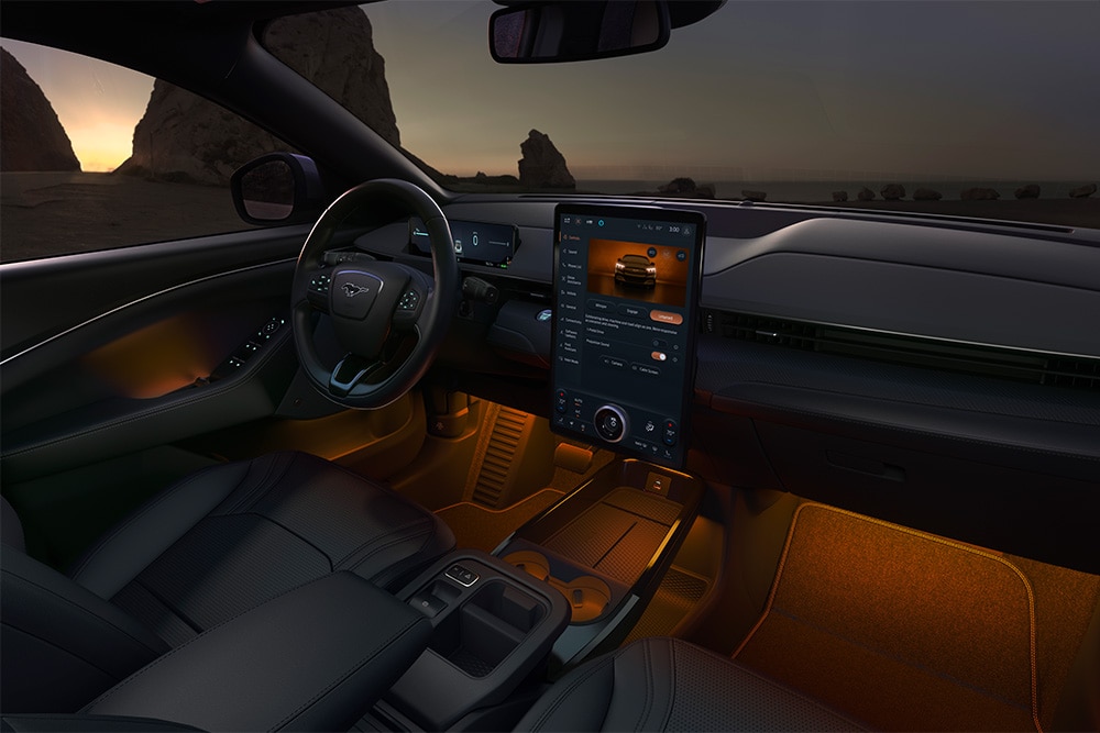 A Ford Mustang Mach-E utastere éjjel. A 15,5"-os SYNC 4 érintőképernyő és a LED-izzós hangulatvilágítás narancsszínű.