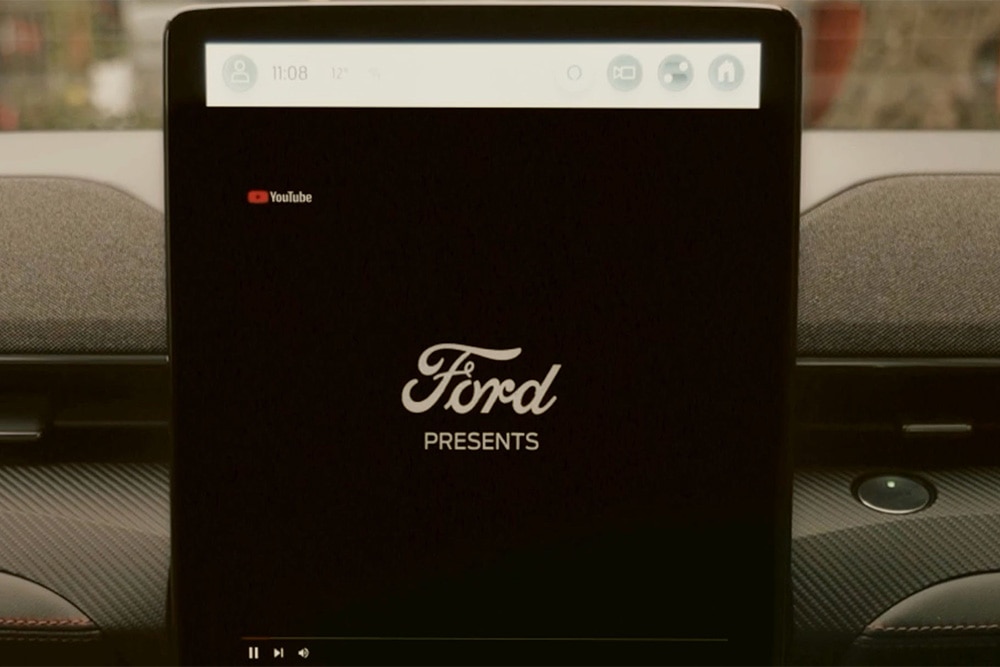 15,5"-os SYNC 4 érintőképernyő „Ford presents” feliratú grafikával, bemutatva a video streaminget.