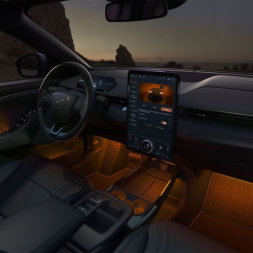A Ford Mustang Mach-E utastere éjjel. A 15,5"-os SYNC 4 érintőképernyő és a LED-izzós hangulatvilágítás narancsszínű.