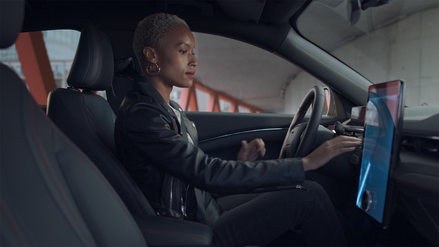 Woman sitting in a Ford Mustang Mach-E using the Next Generation touchscreen