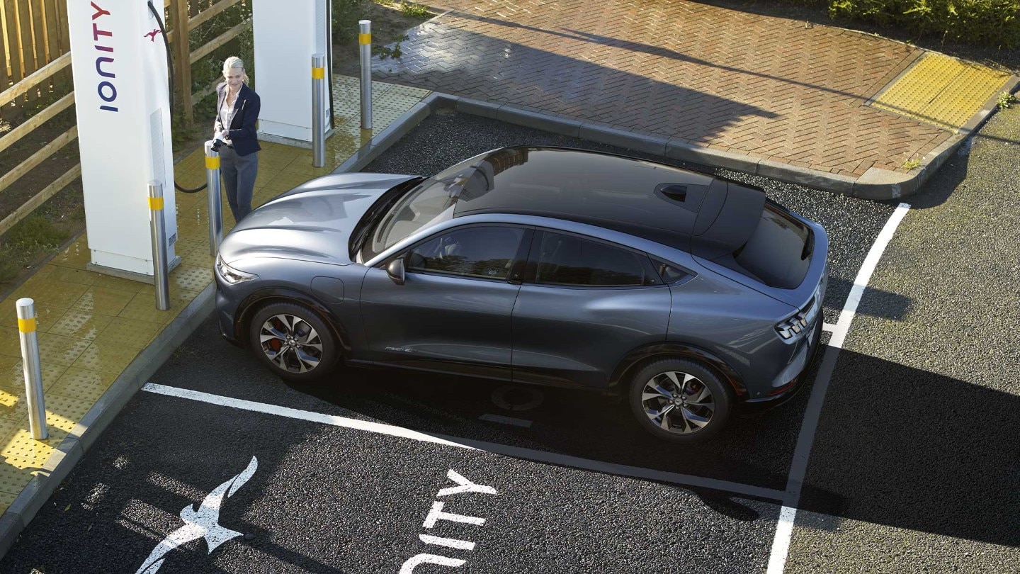 A woman charging an all-new Ford Mustang Mach-E at an IONITY charging station