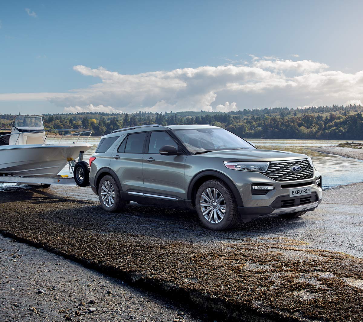 Ford Explorer parked in hilly area above lakes with person standing next to it overlooking landscape