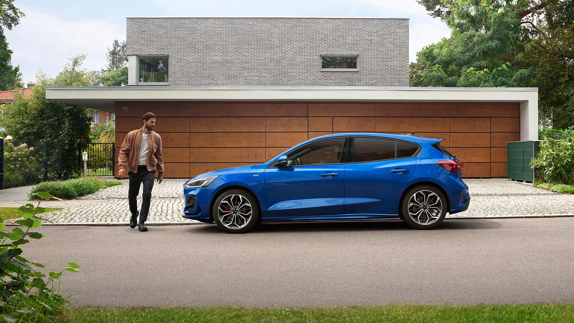 Egy férfi egy ház előtt parkoló kék Ford Focus felé közelít
