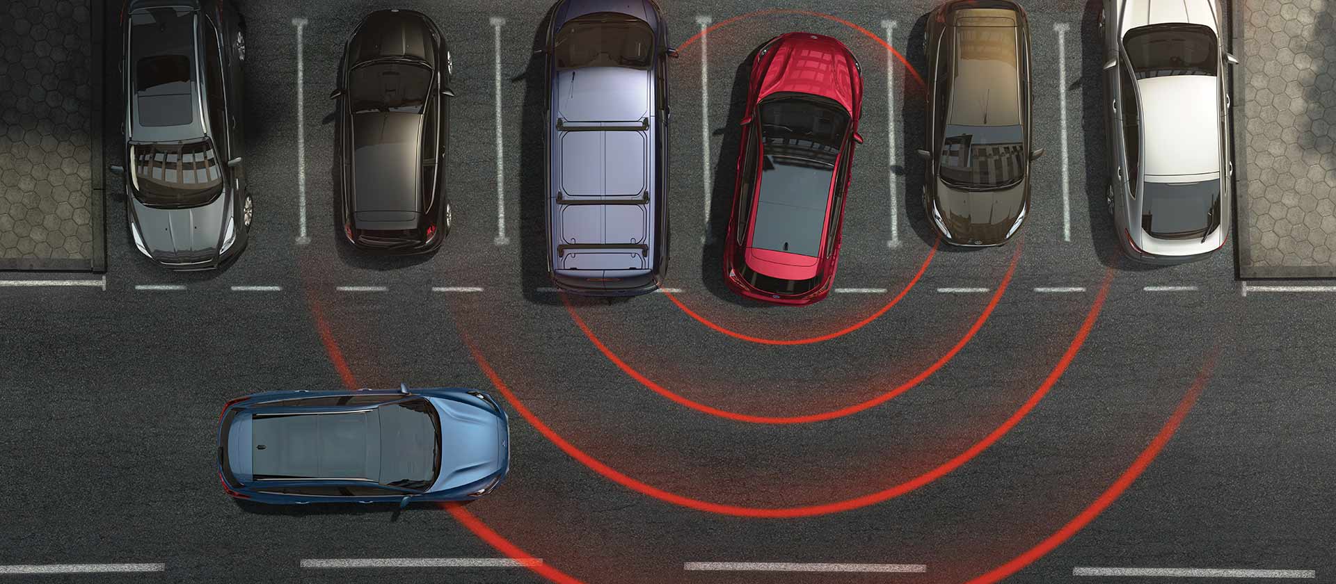 Parkolóhelyek sora felülnézetből. A tolató piros Ford Focusban radarvonalak jelzik a közeli veszélyt.
