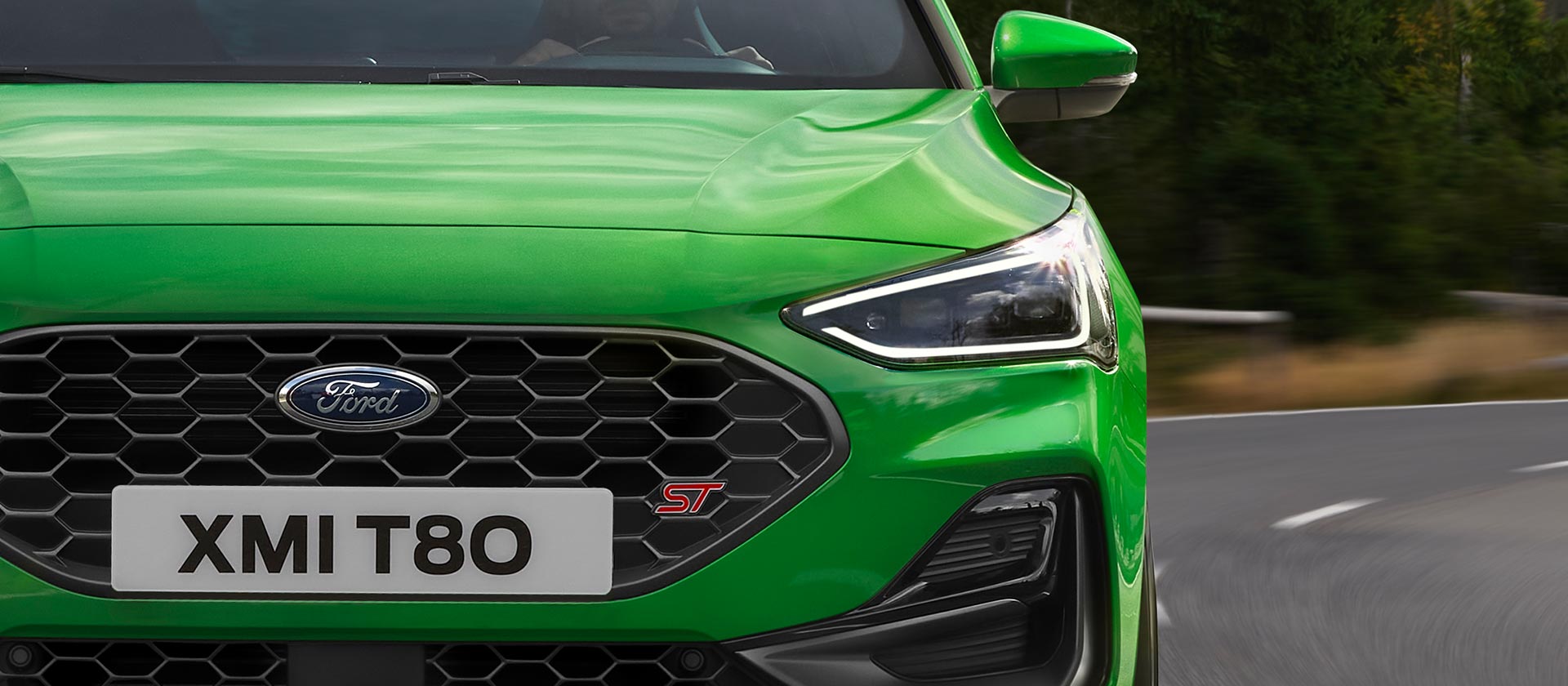 A Mean Green színű Ford Focus ST elölnézete, a méhsejtes hűtőráccsal és az ST logóval.