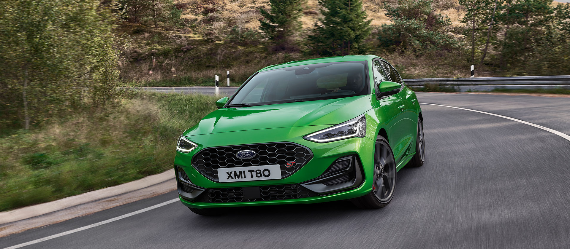 Mean Green színű Ford Focus ST kanyarban halad egy festői úton.