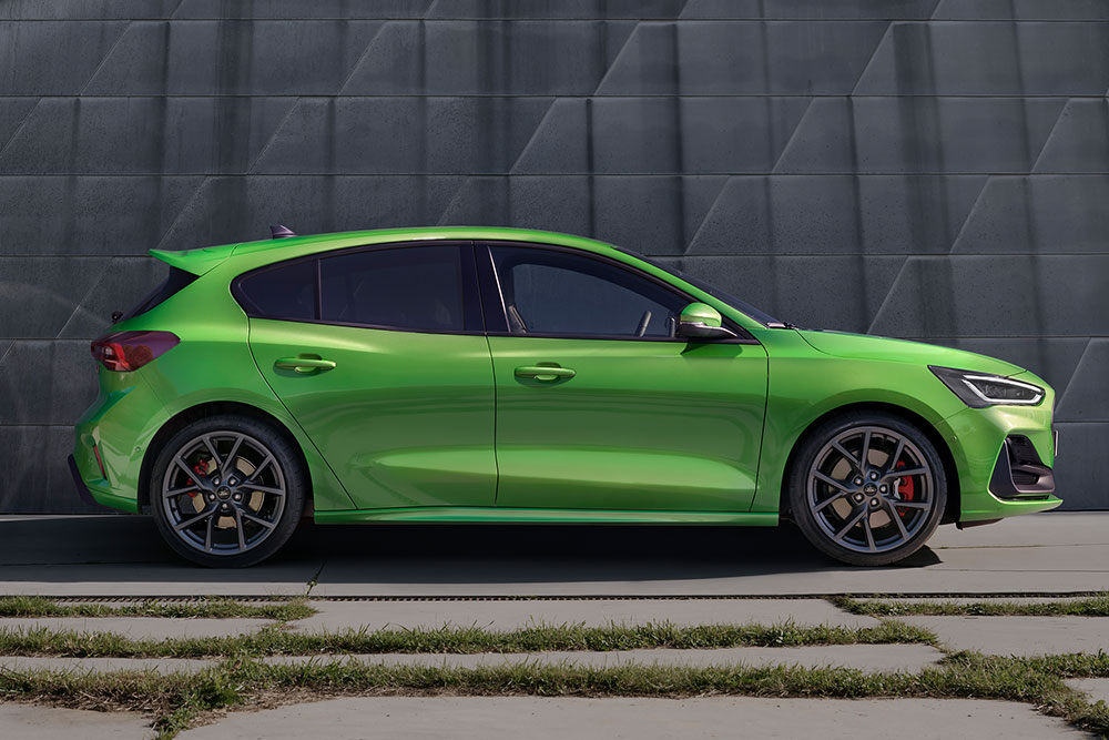 Út szélén parkoló Mean Green színű Ford Focus ST ferdehátú oldalnézetből.