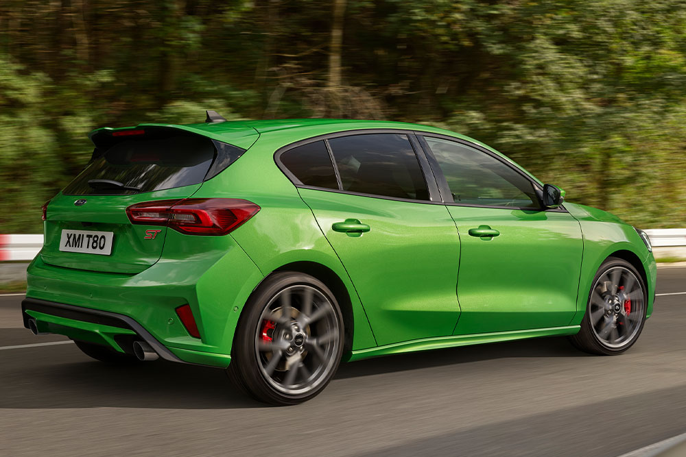  Versenypályán haladó Mean Green színű Ford Focus ST ferdehátú hátulnézetből. 
