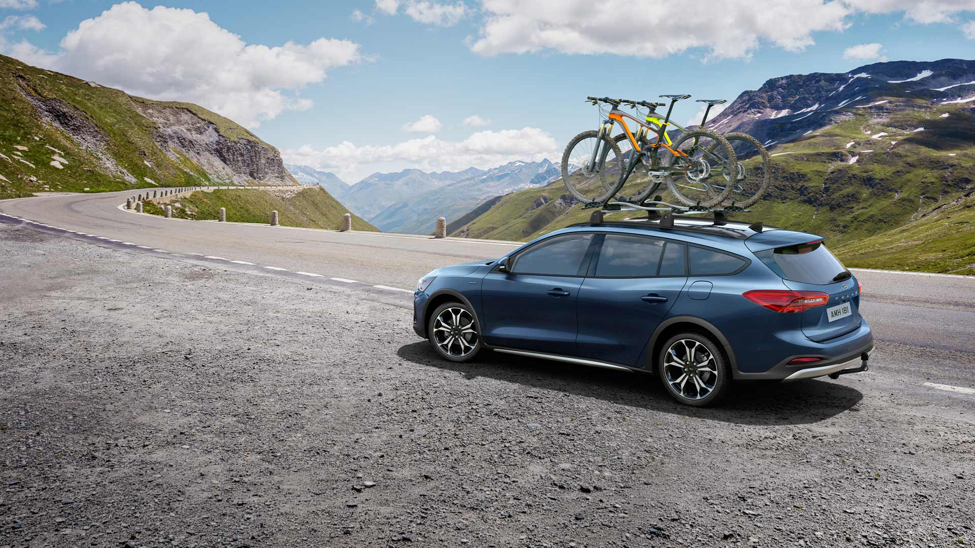 Kék Ford Focus a tetőn kerékpárokkal, festői hegyi úton.