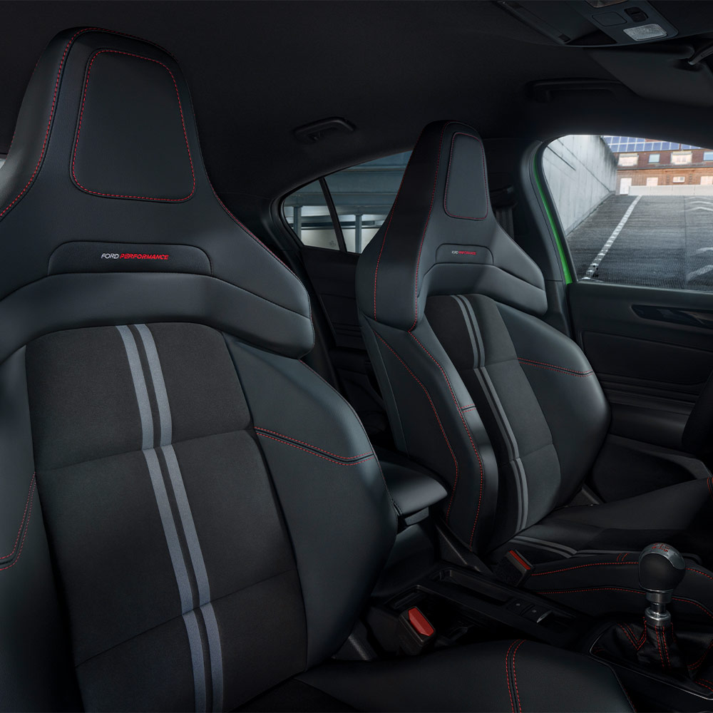 A Ford Focus ST sportülése közelről, sötét kárpitozással és piros kontrasztvarrással.