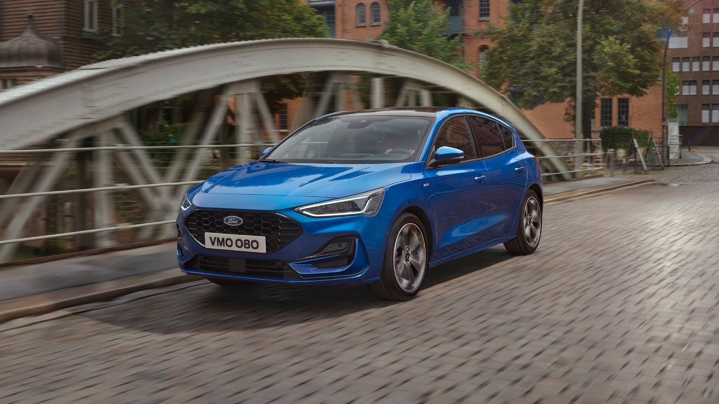 Front three quarter view of a blue Ford Focus driving on a road