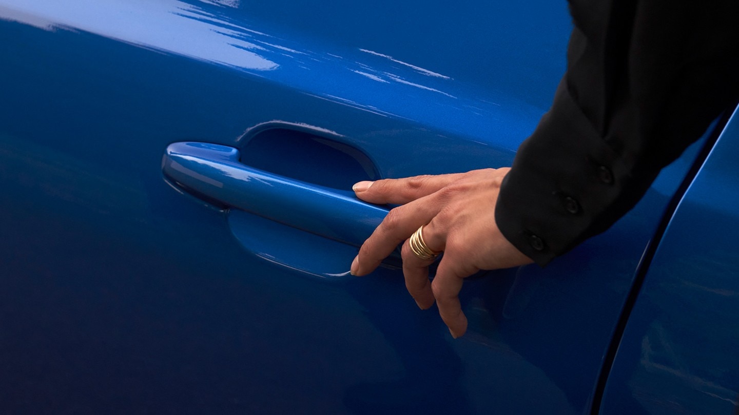 Hand reaching for the handle of front door on a blue Ford Focus