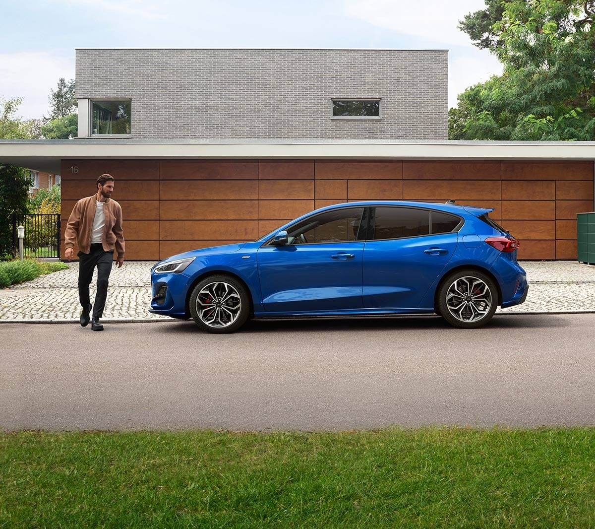 Man approaching a blue Ford Focus parked outside a house