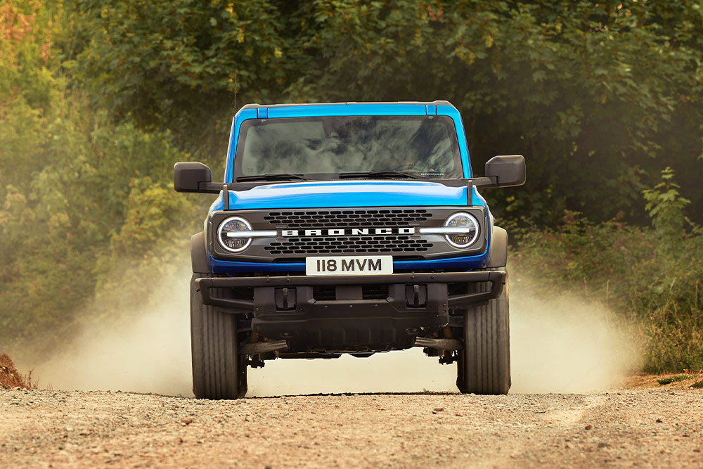 Egy földúton haladó kék Ford Bronco elölnézetből.