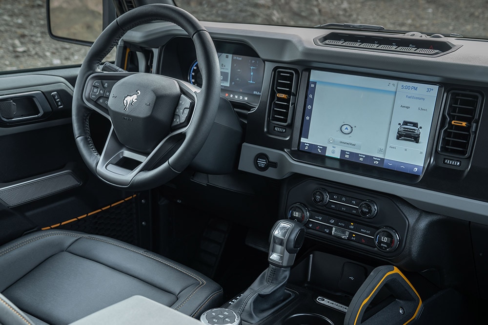 A Ford Bronco belső terének képe a bőr kormánykerékkel és a csatlakoztatott érintőképernyővel.