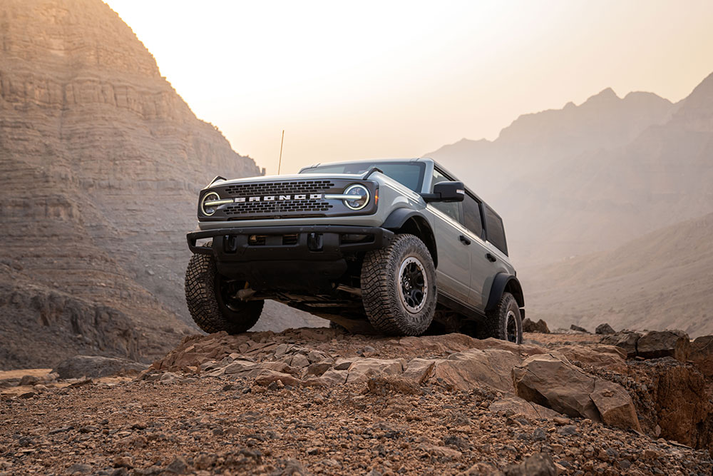 Egy szürke Ford Bronco hegyvidéki környezetben, amint egy sziklás ösvény tetején parkol.