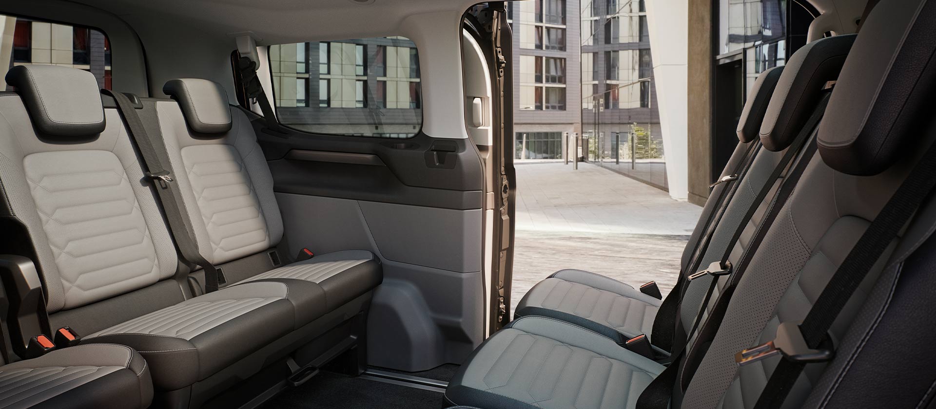 A Ford Tourneo Custom belső tere, több sornyi szürke utasüléssel és panorámatetővel.