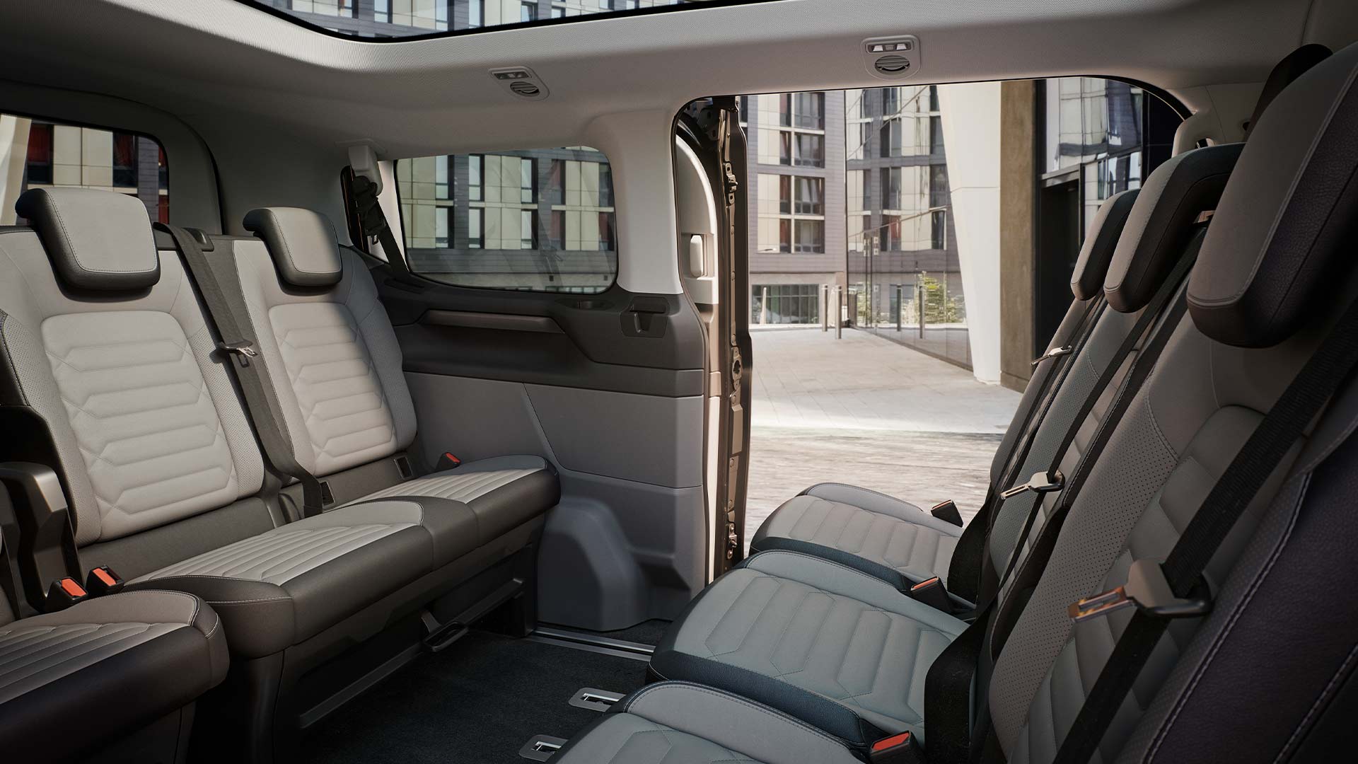 A Ford Tourneo Custom belső tere, több sornyi szürke utasüléssel és panorámatetővel.