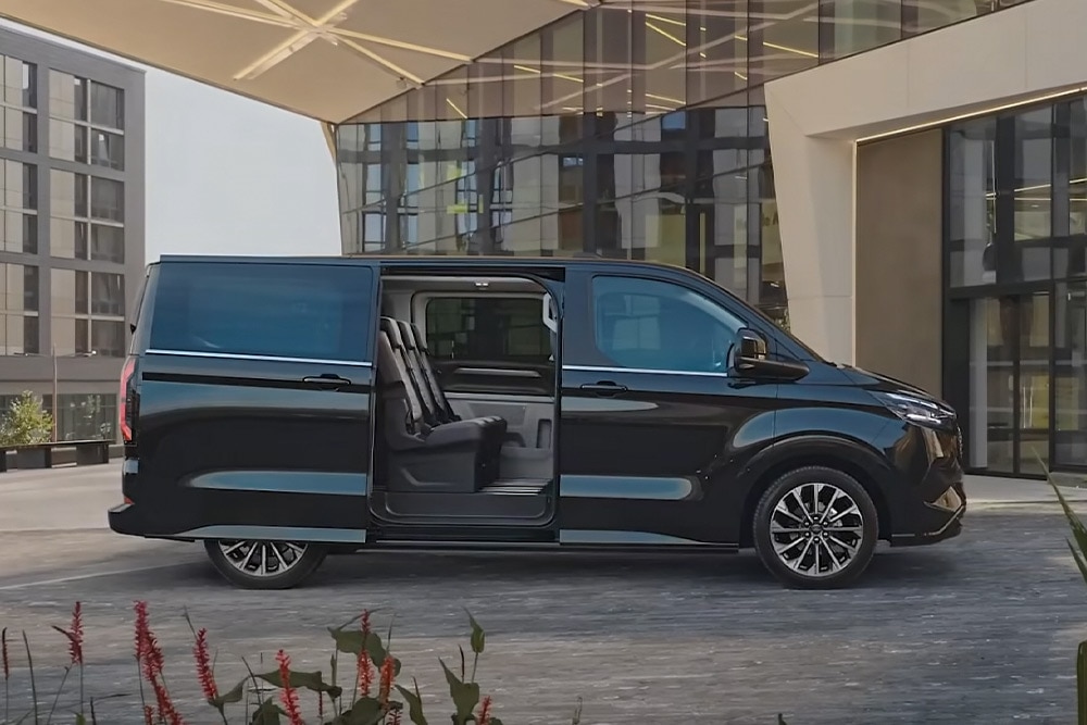 Fekete Ford E-Tourneo Custom parkol nyitott oldalajtóval, belső üléseit mutatva.