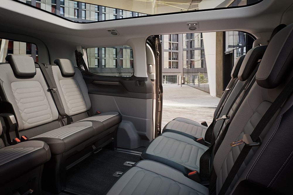 A Ford Tourneo Custom belső tere, több sornyi szürke utasüléssel és panorámatetővel.