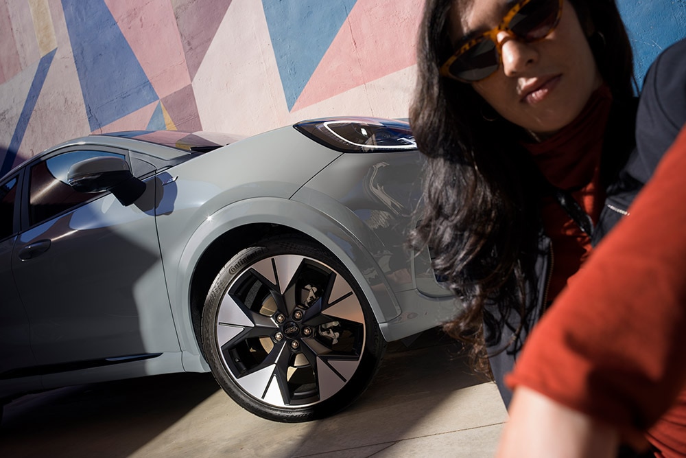 Közelkép egy EcoBoost® benzinmotoros, szürke Ford Puma® mellett álló személyről.