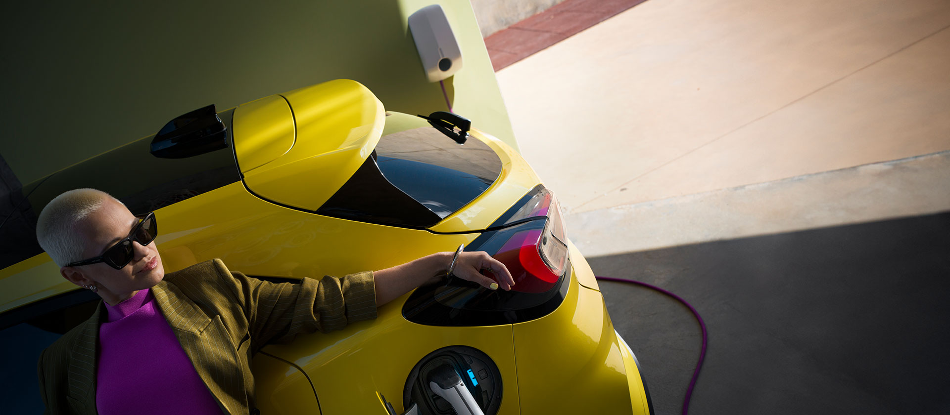 Közelkép egy otthoni Wallboxhoz csatlakoztatott sárga, elektromos Ford Puma Gen-E® hátsó részéről.