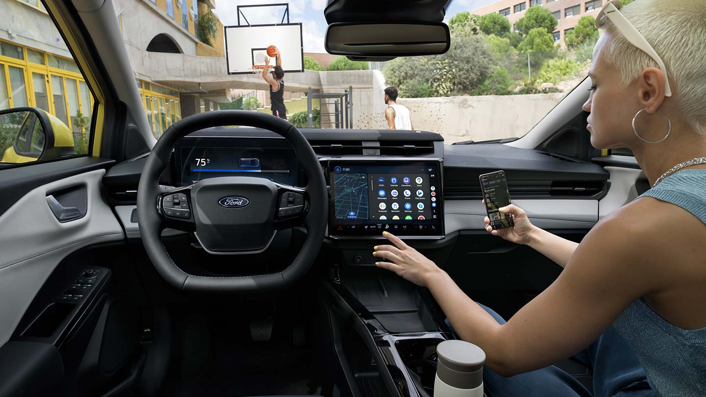 Az elektromos Ford Puma Gen-E® utasterében egy személy a telefonját vezeték nélkül összekapcsolja a nagy érintőképernyővel.