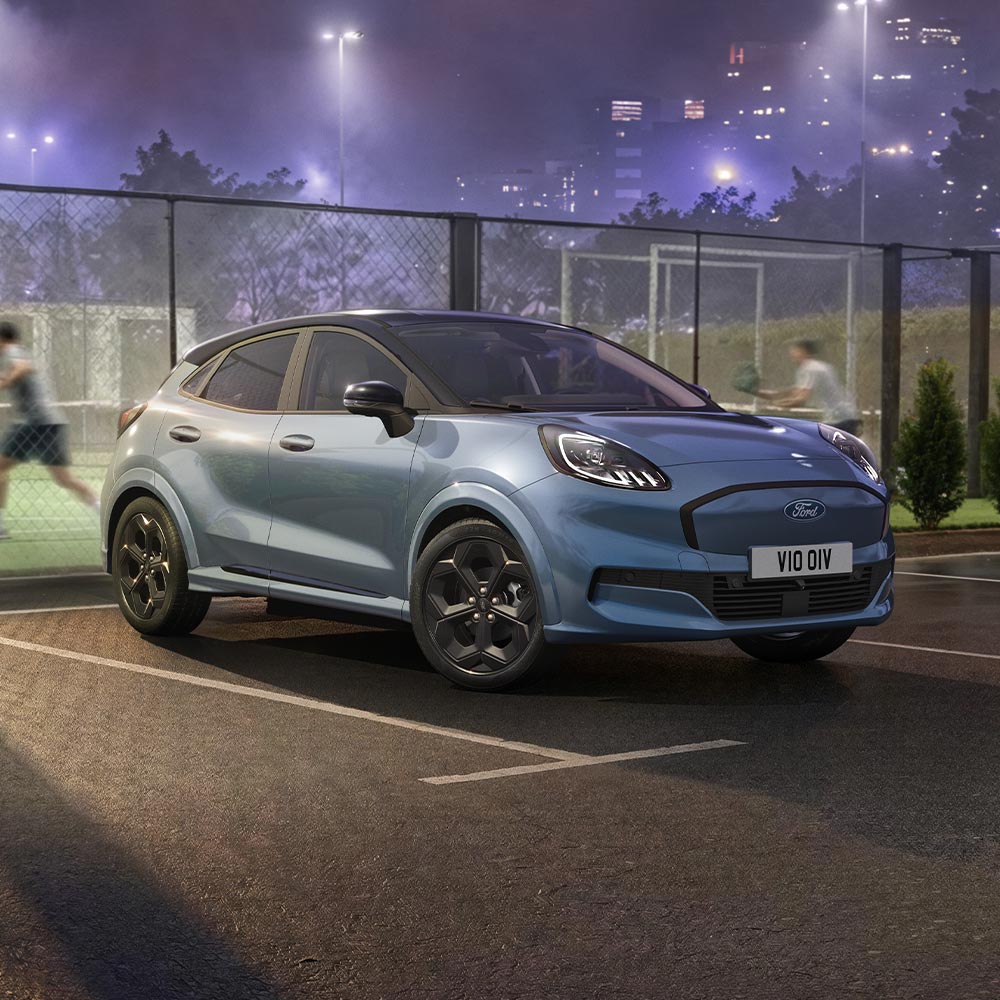 Egy limitált kiadású, Vapour Blue színű Ford Puma Gen-E BlueCruise technológiával, egy szabadtéri padelpálya mellett parkol.