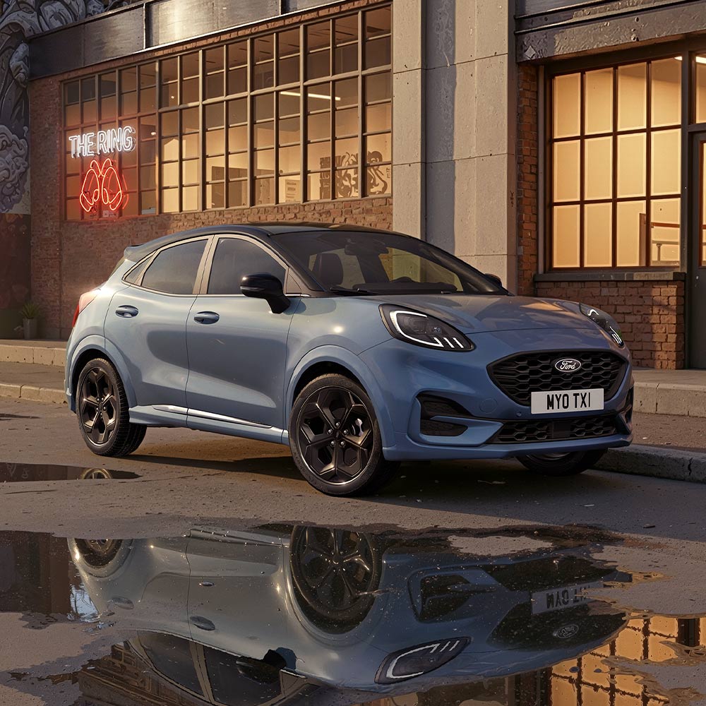 Egy limitált kiadású, Vapour Blue színű Ford Puma egy halványan megvilágított városi úton parkol éjszaka.