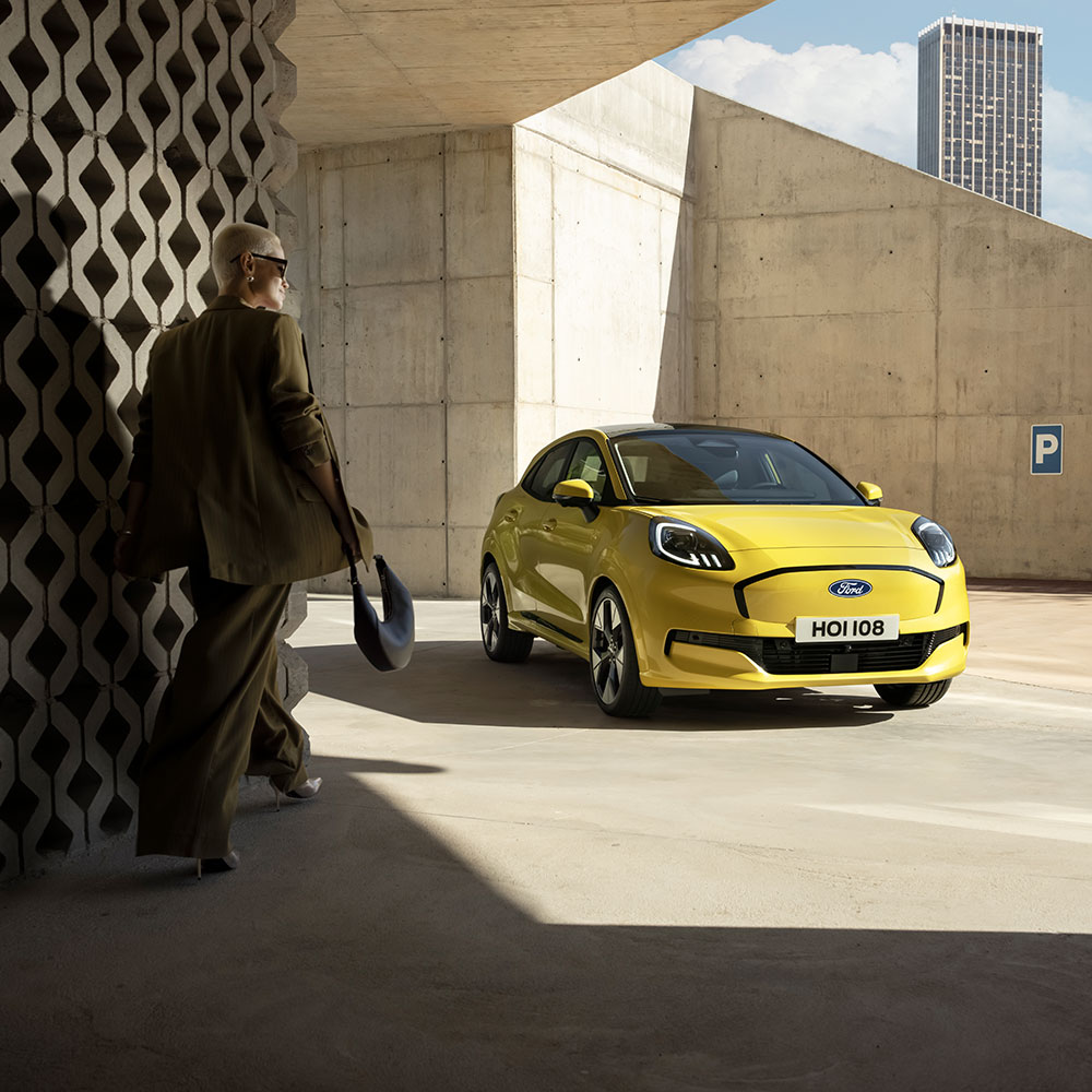 Egy személy halad egy sárga színű új, elektromos Ford Puma Gen-E® jármű felé.