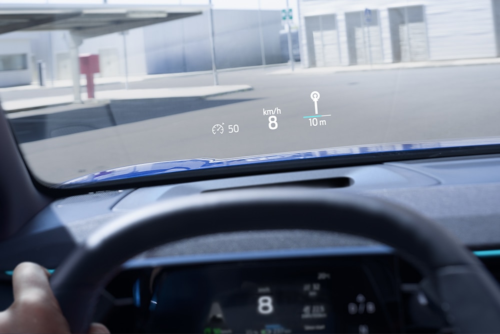 Közelkép az elektromos Ford Capri® szélvédőre vetített kijelzőjéről, mely a legfontosabb vezetési adatokat mutatja.