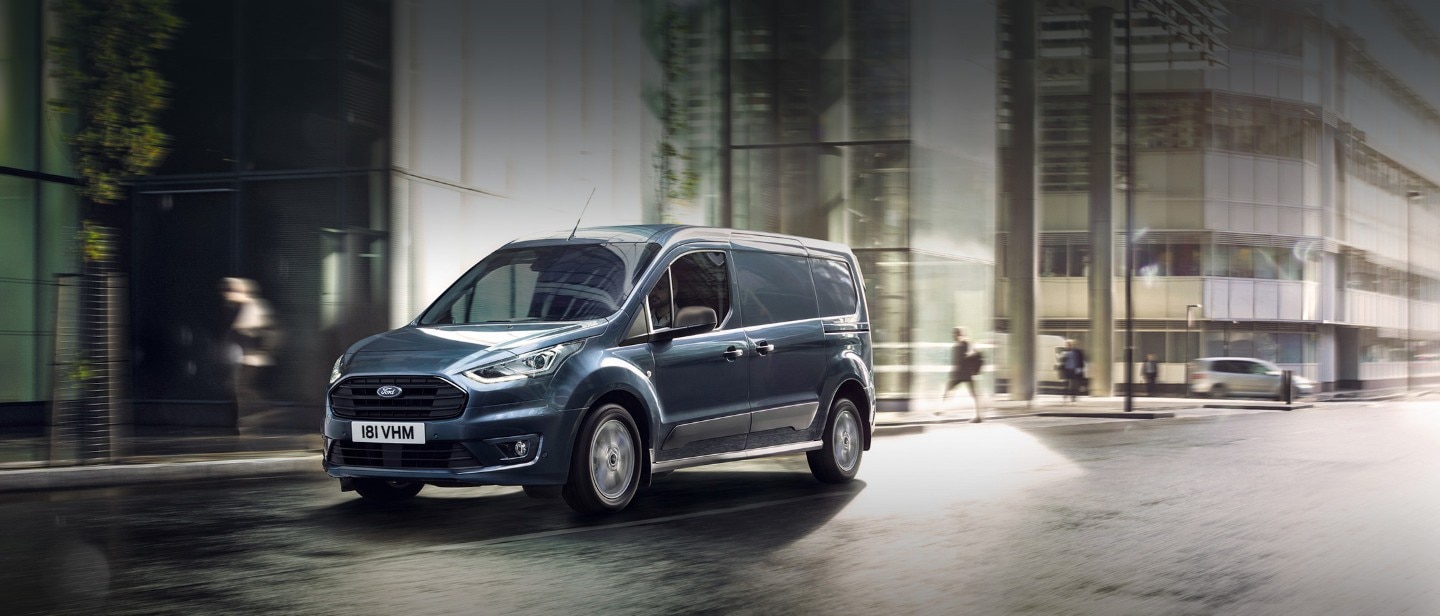 Blue Ford Transit Connect driving in city