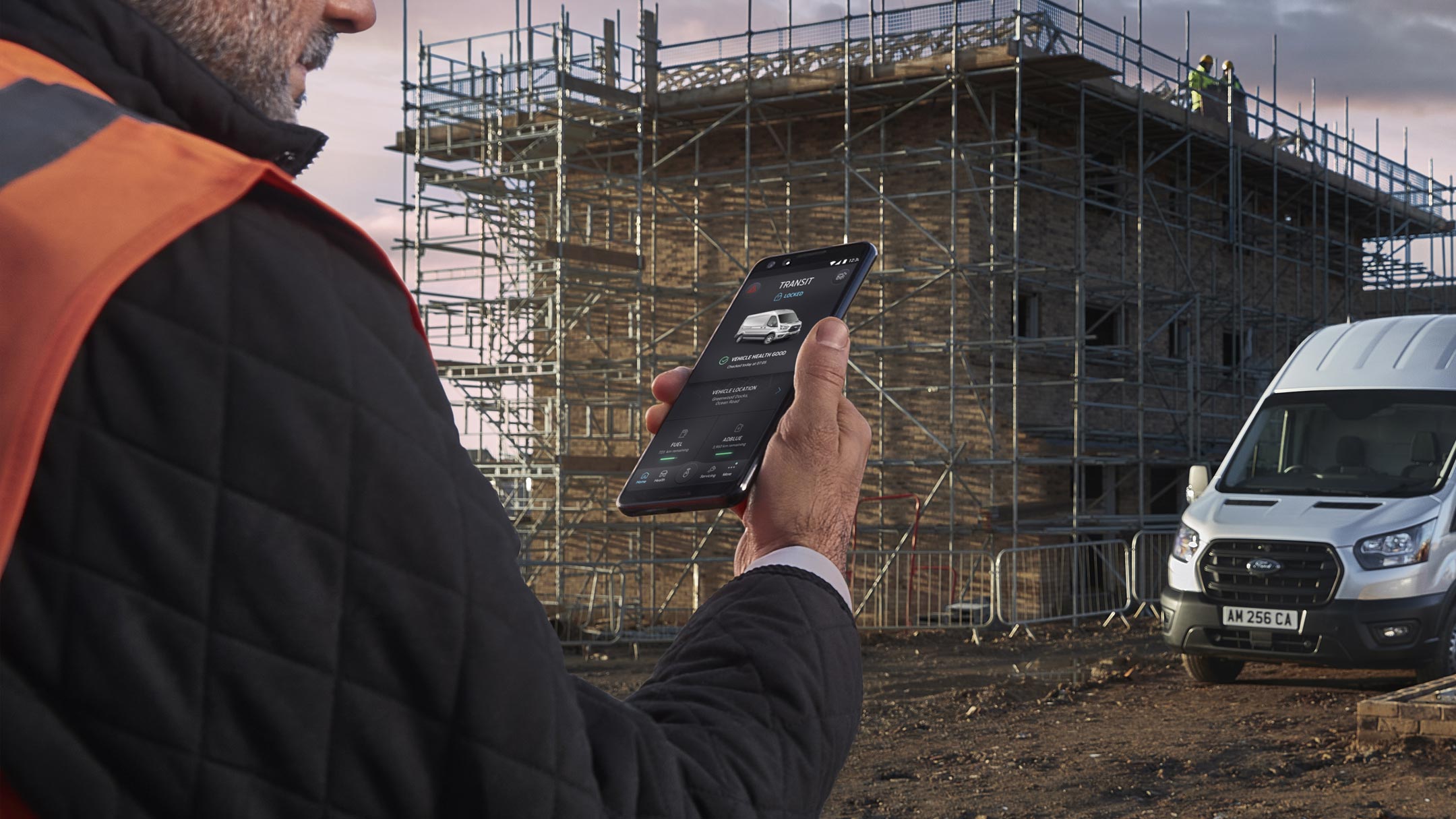 Man holding phone looking at fordpass app at construction site