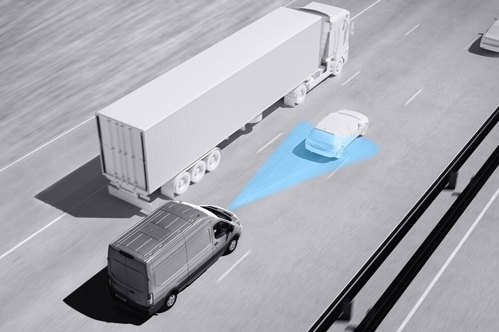 A Ford Transit Van szürkeárnyalatos rajza kék vonalakkal az úton, amely a fejlett vezetéstámogató rendszerek használatát szemlélteti.