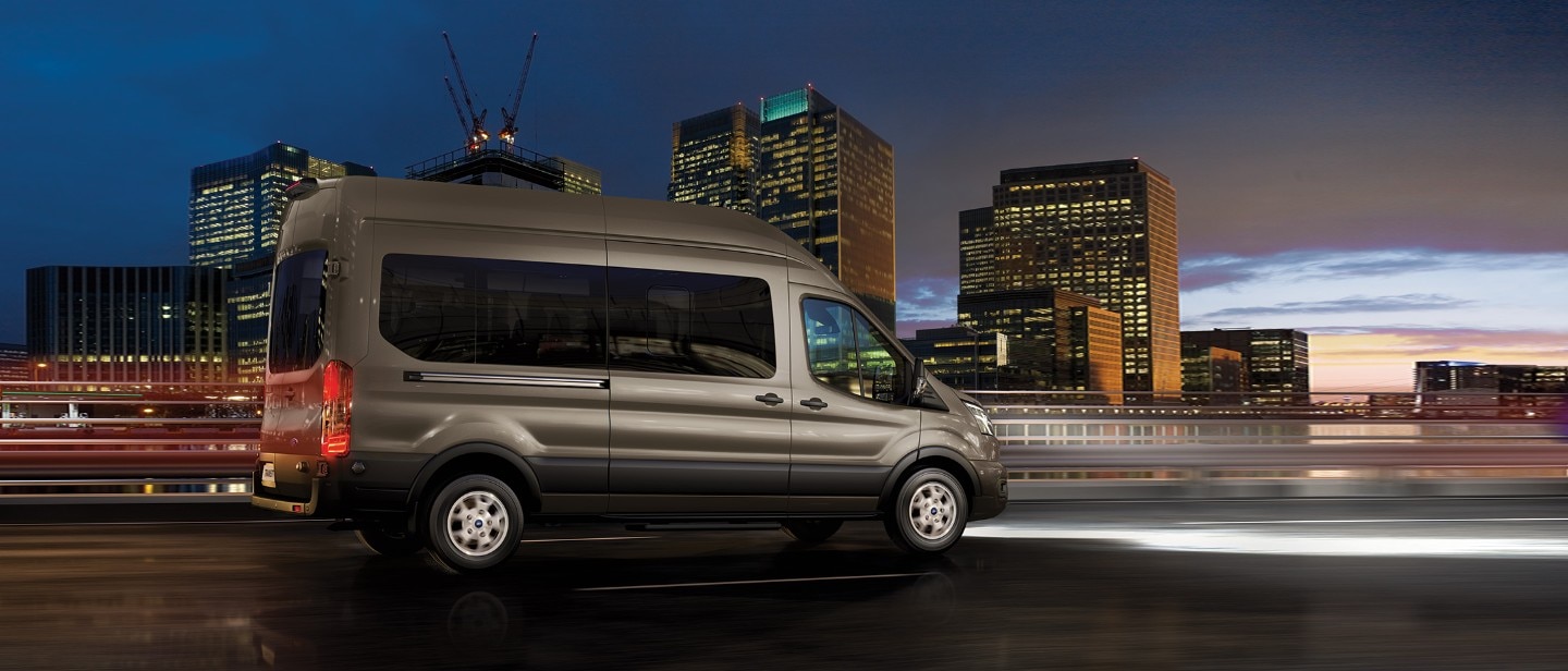 Ford Transit Minibus driving in city after sunset side view