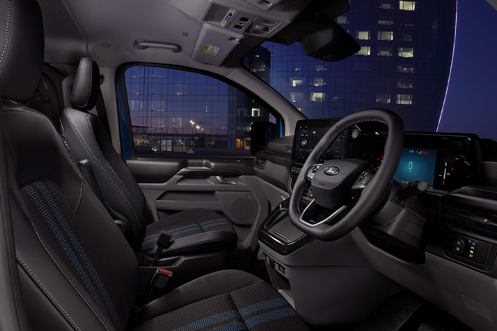 Egy Ford E-Transit Custom elektromos áruszállító belső tere vezető- és utasülésekkel.
