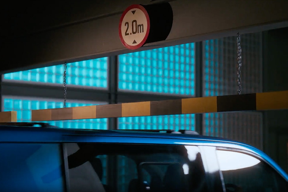 Egy kék Ford E-Transit Custom elektromos áruszállító behajt egy parkolóházba.