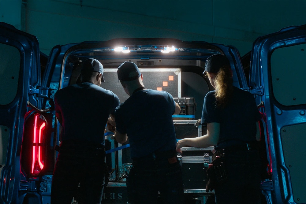 Három ember dolgozik egy Ford E-Transit Custom hátuljában.