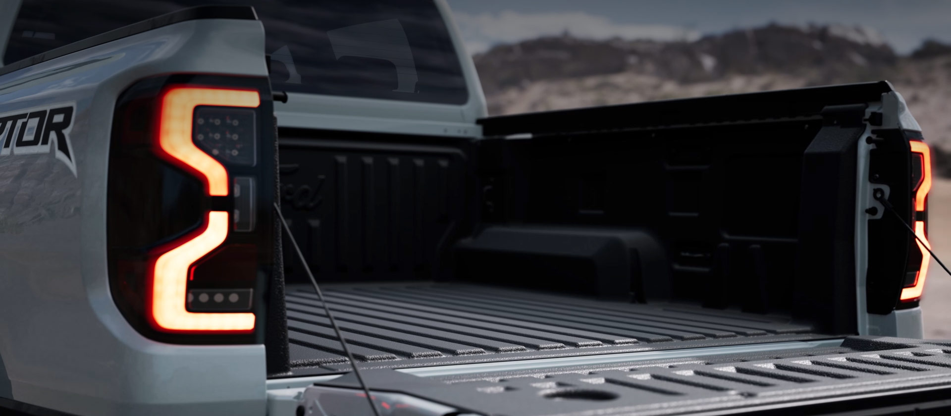 Ezüstszínű Ford Ranger Raptor platója nyitott hátsó ajtóval.
