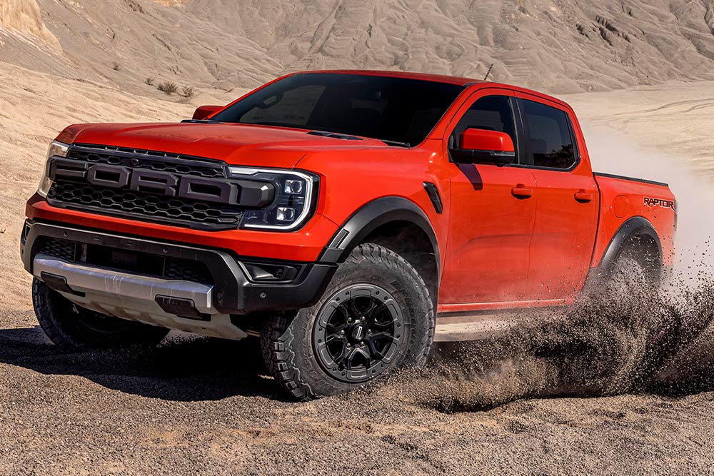 Egy Code Orange színű Ford Ranger Raptor földúton halad.