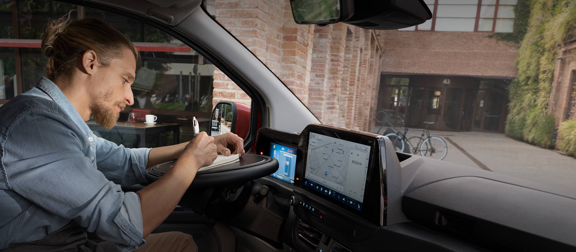 Egy férfi a jegyzetfüzetébe ír egy Ford Transit Customban.