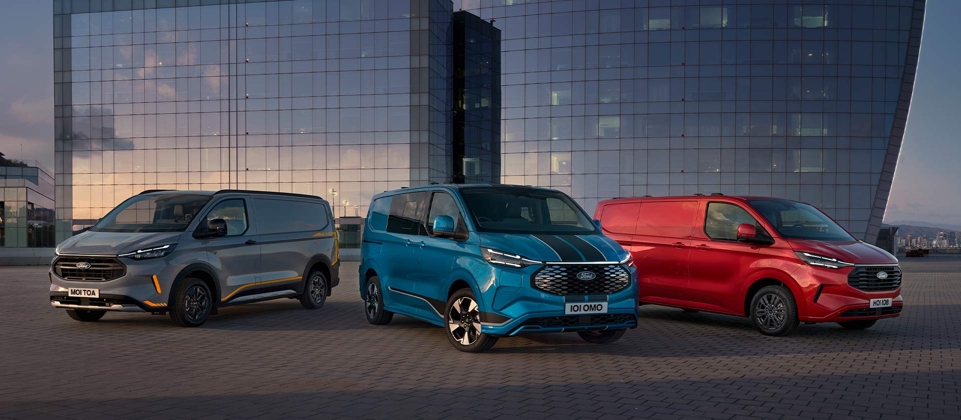 Három parkoló Ford Transit Custom Sport szürke, kék és piros színben. 